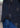 A close-up of a person wearing the Palermo Button Down, a tailored fit black cotton shirt with a skull pattern, paired with blue jeans. The shirt’s side seam and hemline appear above the jeans.