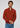 A man stands against a plain light gray background, looking forward with a neutral expression and clasping his hands, dressed in the Milano 1/4 Zip Merino Wool Sweater in rust over a beige shirt and blue jeans.