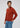 A man with wavy brown hair wears the rust-colored Milano 1/4 Zip Merino Wool Sweater and blue jeans, standing against a plain light background and looking to his left.