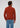 A man stands facing away, wearing the rust-colored Milano 1/4 Zip Merino Wool Sweater and blue jeans, against a plain light background.
