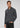Wearing the Milano 1/4 Zip Merino Wool Sweater in dark gray over a light gray shirt and paired with black jeans, a person stands with one hand in their pocket against a plain light background.