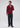 A man stands against a plain background, wearing the Milano 1/4 Zip Merino Wool Sweater in maroon over a collared shirt, paired with dark trousers and brown shoes; one hand is near his neck while the other rests at his side.