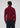 A man with curly hair stands facing away, wearing the Milano 1/4 Zip Merino Wool Sweater in burgundy and dark pants, against a plain light gray background.