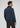 A man stands facing away, wearing the Milano 1/4 Zip Merino Wool Sweater in blue paired with dark pants, set against a plain light background.