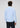 A man stands with his back to the camera, wearing the Adams Stretch Button Down in light blue paired with black pants, set against a plain light gray background.