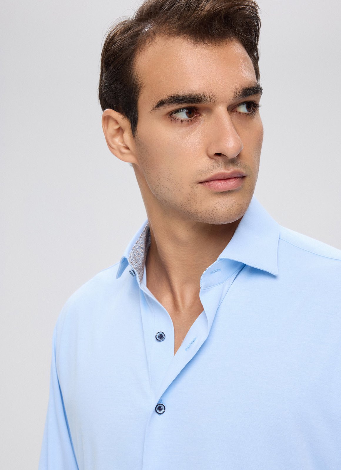 A man wearing a light blue Bergamo Stretch Button Down made of Supima cotton with a patterned inner collar.