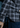 A person wearing the Como Italian Flannel shirt in a navy grey plaid, crafted from luxurious Canclini cotton, paired with blue jeans is shown from the back, with part of their arm and hand visible in the foreground.