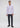 A man stands facing forward, wearing the Ingalls Non Iron Button Down— a light purple dress shirt crafted from wrinkle-resistant cotton—paired with dark trousers and black shoes against a plain, light background.