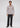 A man stands facing forward, dressed in the Lowry Button Down made from premium European cotton featuring a subtle geometric pattern. He pairs the shirt with dark pants and brown shoes, set against a plain light gray background.