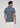 A man stands facing away, wearing the Lyon Reversible Polo—a short-sleeve, navy patterned men’s everyday essential with UPF 50+ protection—paired with crisp white pants against a plain light background.