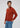 A man with wavy brown hair wears the rust-colored Milano 1/4 Zip Merino Wool Sweater and blue jeans, standing against a plain light background and looking to his left.