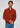 A man stands against a plain light gray background, looking forward with a neutral expression and clasping his hands, dressed in the Milano 1/4 Zip Merino Wool Sweater in rust over a beige shirt and blue jeans.