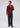A man stands against a plain background, wearing the Milano 1/4 Zip Merino Wool Sweater in maroon over a collared shirt, paired with dark trousers and brown shoes; one hand is near his neck while the other rests at his side.