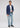 A man stands facing forward against a plain light background, wearing the Northome Sport Coat in Blue Multi Plaid crafted from fine Italian fabric, paired with a white t-shirt, light blue jeans, a black belt, and dark shoes.