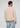 A man stands facing away, wearing the Onamia Reversible 1/4 Zip in beige with gray collar and cuffs, paired with light blue jeans against a plain, light background—a stylish choice for men’s layering pullover options.