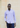 A man wearing the Panasa Stretch Button Down in light purple and dark jeans stands against a beige stone wall with one hand in his pocket.