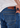 A close-up of a person wearing comfortable Sanded Tapered Stretch Denim jeans and a white shirt, with one hand adjusting the stay-put waistband. The jeans feature visible stitching and a brown leather patch on the back.