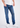 A person wearing comfortable Sanded Tapered Stretch Denim jeans, a white t-shirt, and white sneakers stands against a plain white background. Only the lower half of the body is visible, highlighting the stay-put waistband and modern fit.
