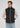 A person wearing a beige long-sleeve shirt, the Stelvio Padded Vest in black, and light blue jeans stands with hands tucked into the vest pockets, glancing slightly to the side against a plain light background—capturing an effortless business casual style with lightweight warmth.