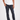 A person stands against a plain background wearing a white t-shirt, Tapered Italian Stretch Denim jeans in dark blue featuring a sag-free waistband, and white sneakers. Only the person’s body from shoulders down is visible.
