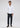 A man stands facing forward wearing the Thurnbeck Stretch Button Down in white, paired with dark trousers and dark shoes, set against a plain light background.