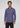 A man with short curly hair wears the Wescott Double Roll Flannel—a long-sleeved, button-up purple shirt crafted from premium European cotton—paired with black jeans, standing against a plain light gray background.