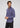 A man with wavy brown hair and a trimmed beard wears the Wescott Double Roll Flannel—a blue button-up shirt made from premium European cotton in a tailored fit—paired with black pants. He stands against a plain light gray background, looking to his left with a neutral expression.
