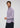 A man with wavy brown hair and a beard is wearing the Zerkel Stretch Button Down, which features fine vertical stripes and wrinkle-resistant fabric, paired with dark trousers as he stands against a plain light background.
